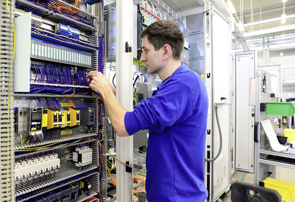 Monteur installiert in einem Betrieb einen Schaltschrank